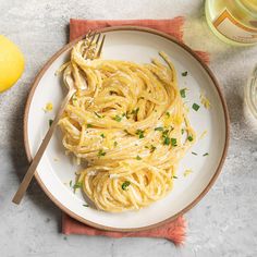 a white plate topped with pasta and parsley next to two glasses of lemonade