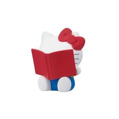 a hello kitty reading a book with a red bow on it's head,