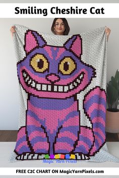 a woman holding up a pink and purple cat blanket with the words smiling cheesie cat on it