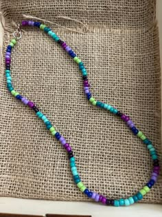 a colorful beaded necklace sitting on top of a piece of burlied fabric