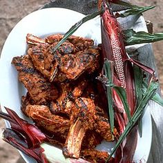 a white plate topped with meat and veggies next to a wooden stick on top of a table