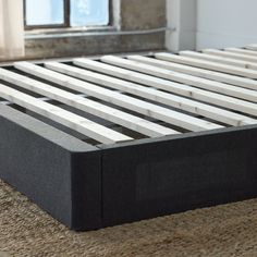 a black and white bed frame sitting on top of a carpeted floor next to a window