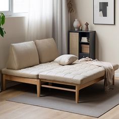 a living room scene with focus on the futon bed and pillows in the foreground