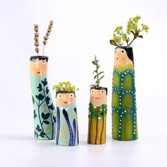 three wooden dolls are holding plants in their hands