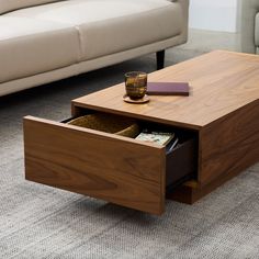 a coffee table with two drawers and a cup on it in front of a couch