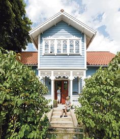 a woman sitting on the steps of a blue house