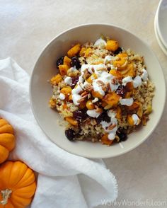 a white bowl filled with food next to two small pumpkins on top of a table