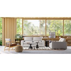 a living room filled with furniture next to large windows and lots of plants on the wall