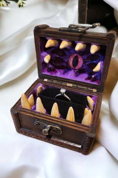 an open wooden box with fake teeth inside on a white cloth covered tableclothed surface