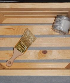 a paint brush sitting on top of a wooden table next to a can of paint