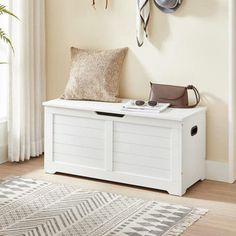 a white bench sitting in front of a window next to a wall with hooks on it