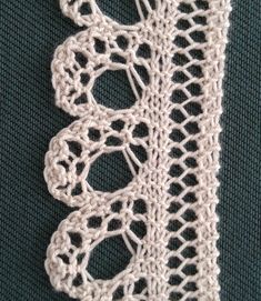 a piece of white crocheted fabric on a green tablecloth with two holes in the middle