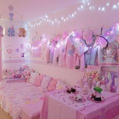 a room decorated in pink and white with lots of stuffed animals on the walls, lights strung from the ceiling