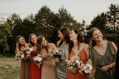 a group of women standing next to each other holding bouquets in their hands and laughing