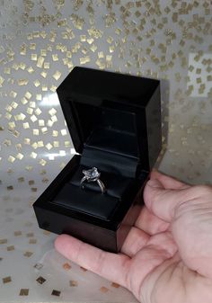 a hand holding a ring in a black box