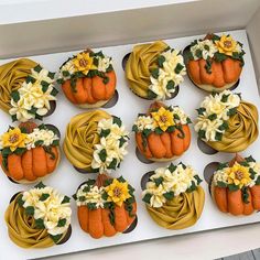 twelve cupcakes decorated with yellow and white flowers on top of each other in a box