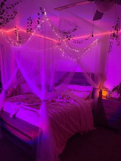 a bed that has some lights on it in the room with purple lighting around it