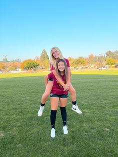 two girls are posing for the camera on a soccer field with their arms around each other