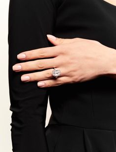 a woman's hand with a ring on top of her finger, wearing a black dress