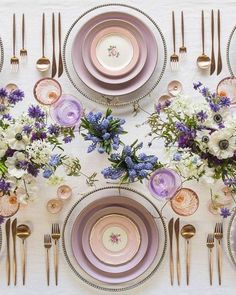 the table is set with purple and white plates, silverware, and floral centerpieces