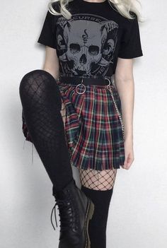 a woman with white hair wearing a black t - shirt, plaid skirt and knee high boots