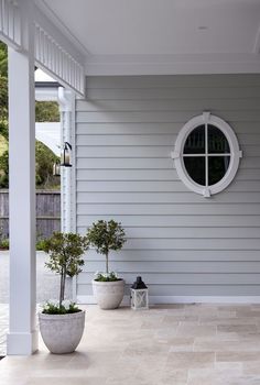 two potted plants sitting on the front porch next to a white door and window