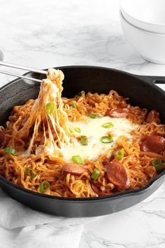 a skillet filled with noodles, meat and cheese