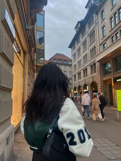 a woman is walking down the street with her back to the camera