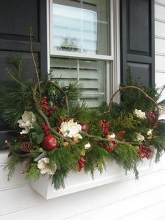 a window sill decorated with evergreen, berries and pine cones