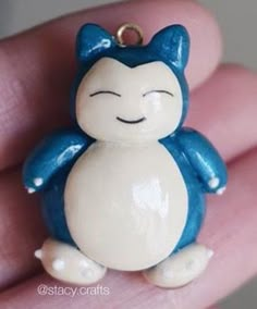 a small blue and white cat charm sitting on someone's hand with it's eyes closed