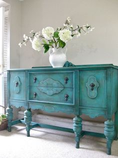 a blue dresser with flowers in a vase on top