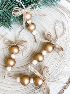 some ornaments are hanging on a tree stump with twine and burlap ribbons