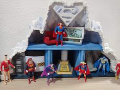 some action figures are standing in front of a tv set with supermans on it