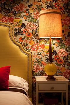 a bed with a yellow headboard next to a night stand and lamp on top of it