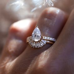 a woman's hand with a ring on it and a feather in the background