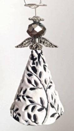 a bell ornament hanging from a hook on a white background with black leaves