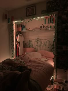 an unmade bed in a room with lights on the headboard and shelves above it