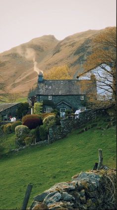 a house on the side of a hill with mountains in the background