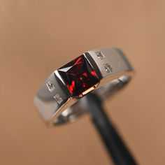 It is a natural garnet ring, princess cut, measures 6mm*6mm, weight about 1.51 cts. The basic metal is sterling silver and plated with rhodium. The accents are CZs. To change the metal to a solid gold (white/rose) or platinum is also available, please ask for a quotation if you want. You can also go to my shop Home for more elegant rings: https://www.etsy.com/shop/godjewelry?ref=hdr_shop_menu emerald is May birthstone More emerald rings: https://www.etsy.com/shop/godjewelry?ref=seller-platform-m Garnet Rings For Men, Blood Stone Ring, Silver Rings For Men, Exclusive Engagement Rings, Garnet Ring Vintage, Elegant Rings, January Birthstone Rings, Emerald Rings, Pink Sapphire Ring