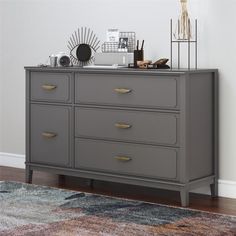 a gray dresser sitting on top of a wooden floor next to a rug and wall