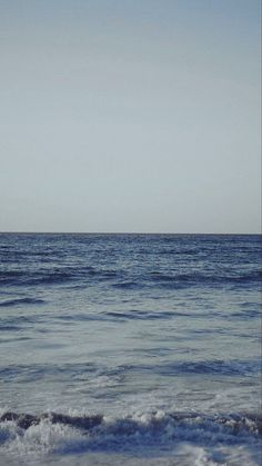 an ocean view with waves crashing in the foreground and a lone boat on the horizon