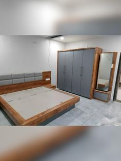 an empty room with a bed, mirror and cupboards in the corner on the floor