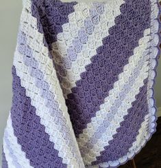 a purple and white crocheted blanket sitting on top of a wooden chair