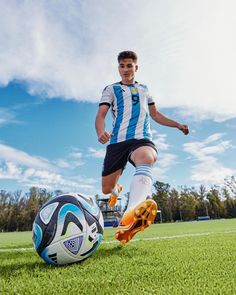 a young man kicking a soccer ball on a field