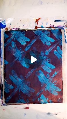 an abstract painting with blue dragonflies on red and purple background, in the center is a video player