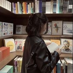 a woman standing in front of a book shelf filled with books