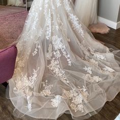 the back of a wedding dress with white flowers on it, in front of a mirror