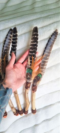 hand holding three feathers on top of a bed