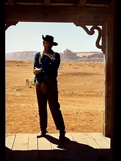 a man wearing a cowboy hat standing in an open doorway