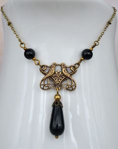 "VINTAGE ELEMENTS Unique Jewellery, Handmade from Vintage Inspired, Original Designs. Art Nouveau Style antiqued Brass Necklace with Jet Black Czech Glass Beads and central Filigree Lovebirds detail. This Necklace has a fine antiqued brass satellite chain and measures 171/2 \" (43.5cm) plus a 3\"(7.5cm) extender Chain." Vintage Black Brass Necklace, Black Vintage Necklace With Charm, Indian Choker Necklace, Antique Gold Earrings, Bijoux Art Nouveau, Art Nouveau Earring, Glass Drop Earrings, Vintage Elements, Art Nouveau Jewelry